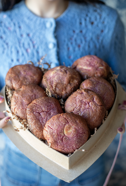Heart-shaped box of white chocolate raspberry rose cookies with a pink ribbon tied on the lid.