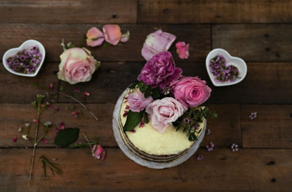 Decorative cake with pink and purple flowers on a wooden surface