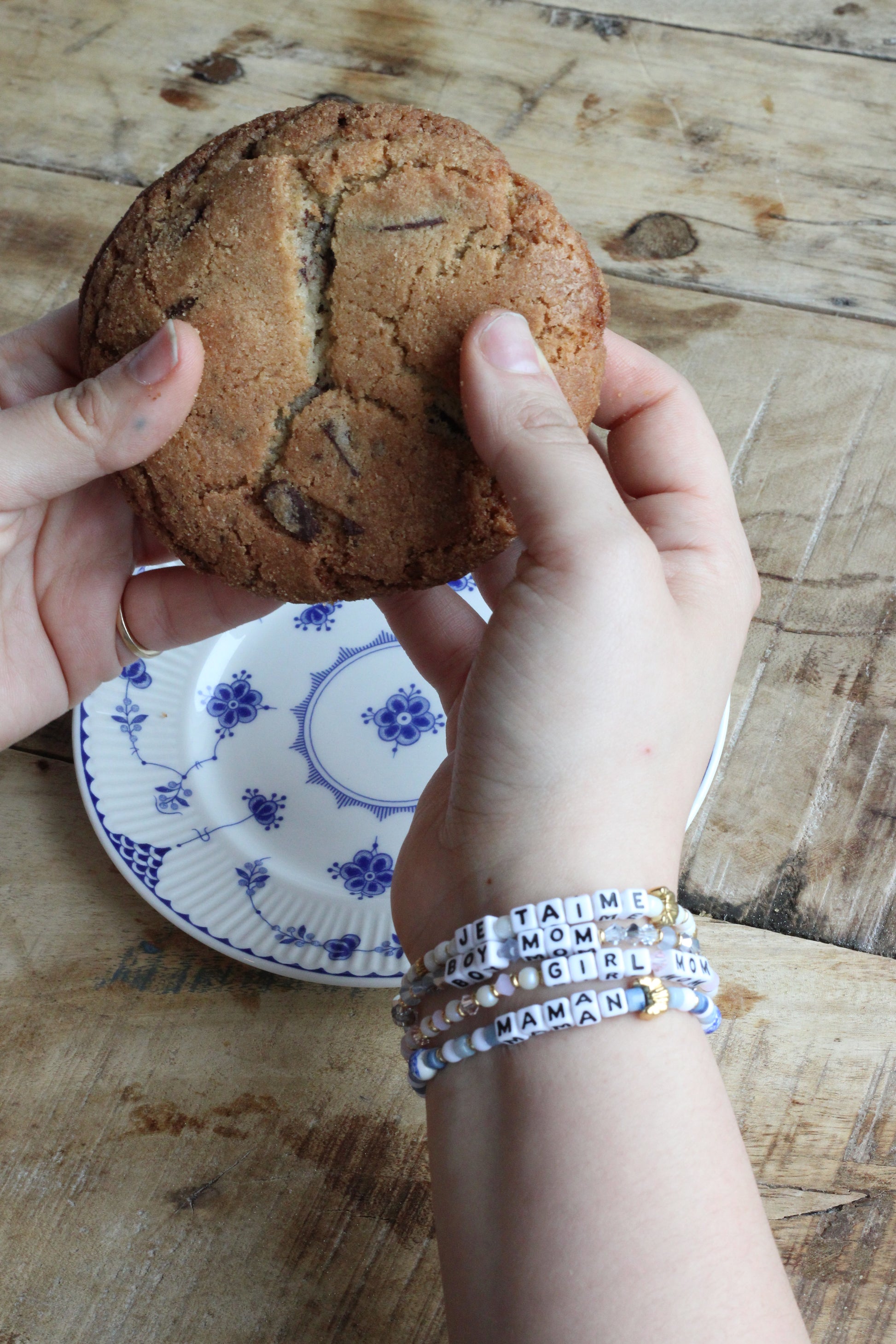 maman x Little Words Project mom bracelets worn on wrist — hands breaking a cookie